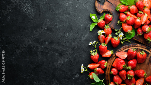 Fresh strawberry with leaves on a black stone background. Berries Top view. Free space for your text.