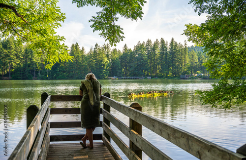 Fototapeta Naklejka Na Ścianę i Meble -  Woman enjoying lake view in forest standing on wooden pier