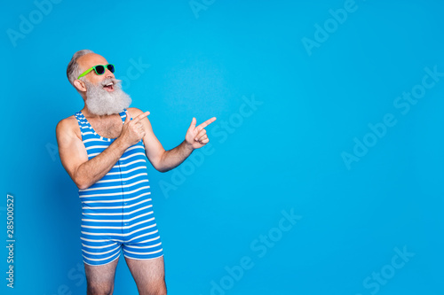 Portrait of his he nice attractive confident cheerful cheery glad gray-haired man pointing ad advert sale discount black Friday copy space isolated on bright vivid shine blue background