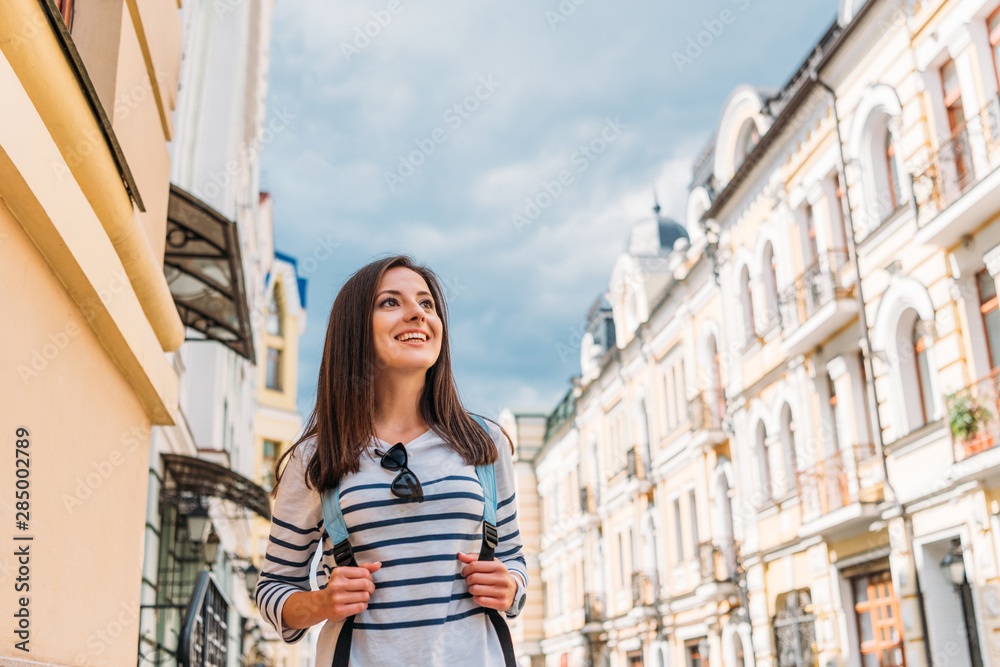 low angle view of happy girl with backpack near buildings