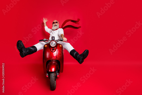 Full size photo of funny pensioner with eyeglasses eyewear raising his palm screaming driving his bike wearing white jumper trousers pants boots isolated over red background