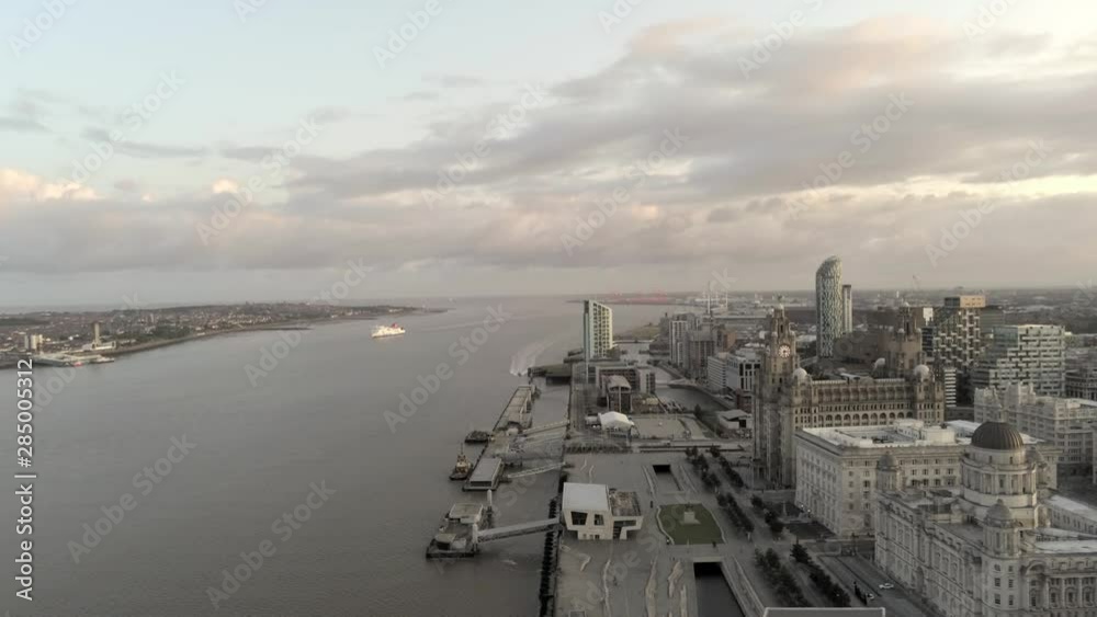 Liverpool waterfront cityscape aerial dolly right across ship on river seaport pier high rise buildings at sunrise. Liverpool waterfront cityscape aerial dolly right across ship on river seaport pier high rise buildings at sunrise.