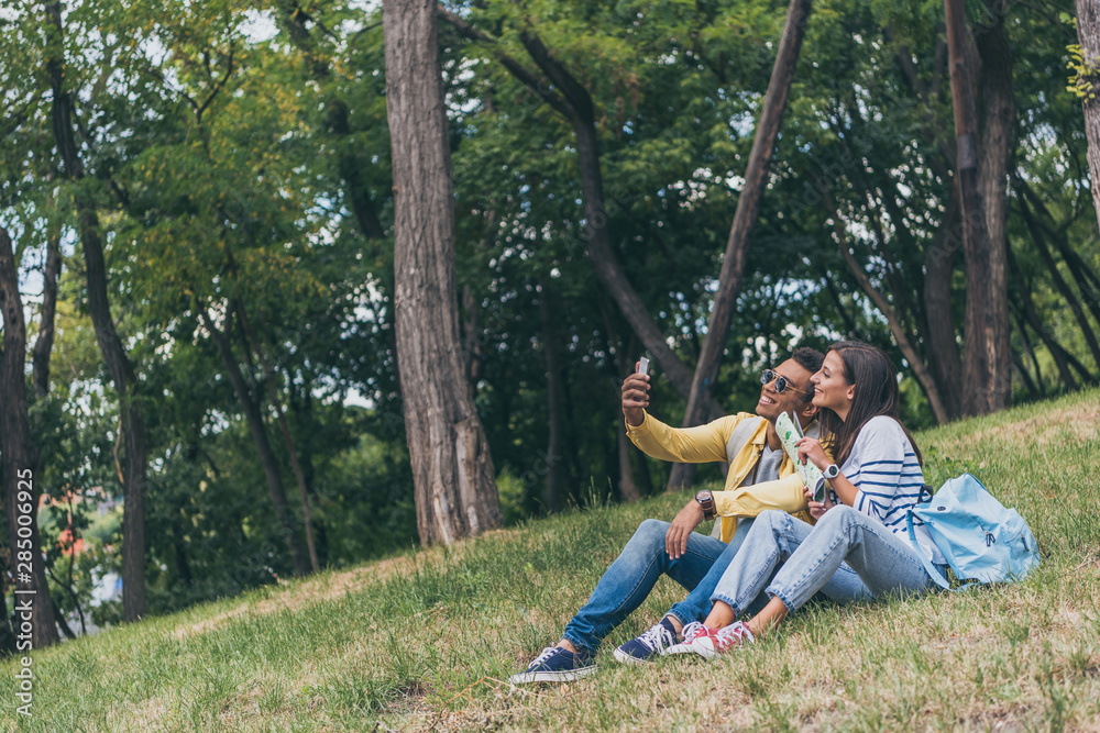 happy mixed race man taking selfie with cheerful girl while sitting on grass happy mixed race man taking selfie with cheerful girl while sitting on grass