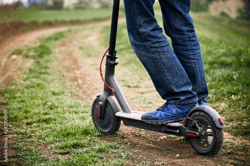 A man rides a scooter in the countryside in summer.