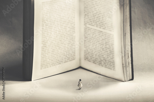 Картината върху платно small woman approaches with fear the power of the knowledge of a giant book