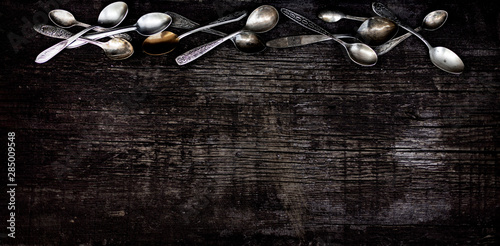 Vintage cutlery - spoons, forks and knives on an old wooden background.