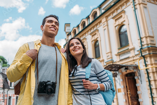 Photography low angle view of happy mixed race man and cheerful girl smiling against blue sk