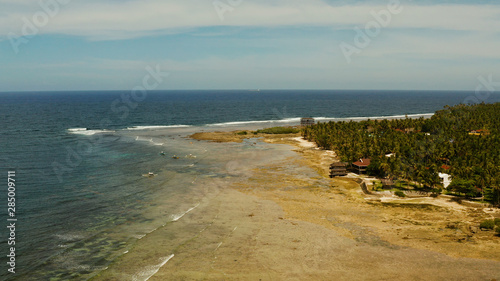 Surf spot with surfers on the waves at sunset on the island of Siargao  cloud 9  Philippines. Aerial view.