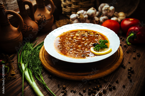 Saltwort with meat lemon and olive on a wooden table decorated with fresh vegetables and spices. Traditional soup with different types of meat