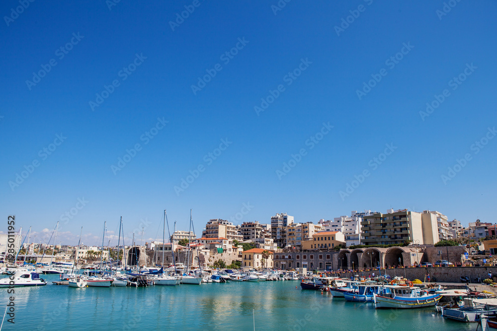 The harbor of Heraklion with ruins of Venetian era buildings and numerous yachts and boats in port, Crete, Greece.