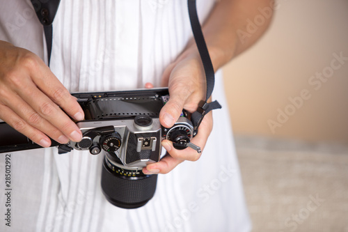 Contrast between old and modern times: a young woman fiddles with her vintage camera hanging from her neck