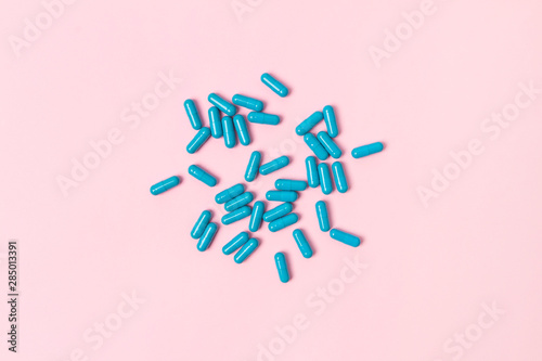 Blue pills at pink background. Flat lay top view.