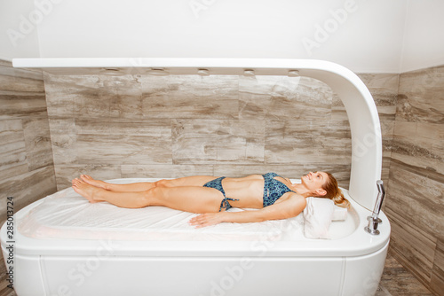 Woman lying under the hot shower in the spa photo