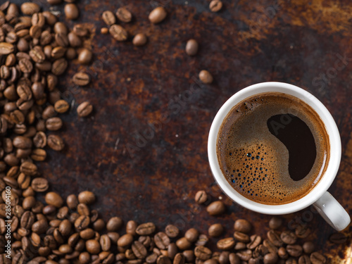 white espresso coffee Cup and roasted beans on old rusty brown background. copy space