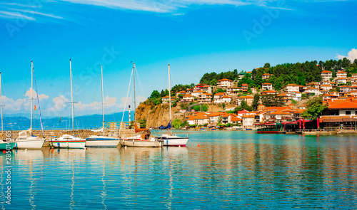 North macedonia. Ohrid. Pier with different sailboats and hill with buildings photo