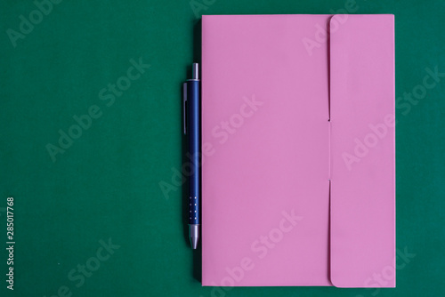 The notebook and pen is on green paper background photo