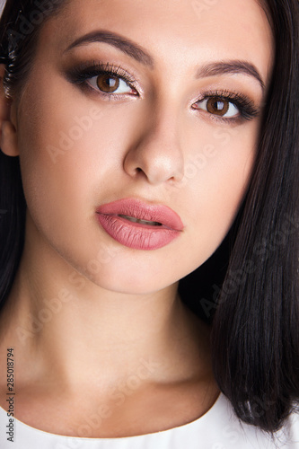 Close-up portrait of sensuality young brunette girl with brown eyes, woman with stylish make up is looking straight and posing cute, beauty concept, free space