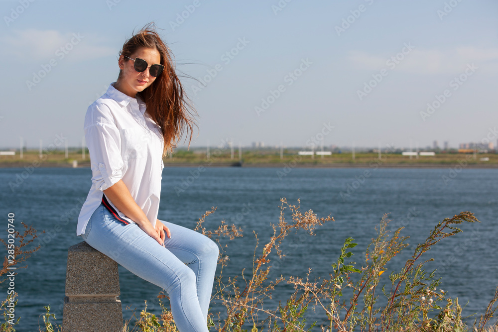 Picture of smiling pretty girl sitting on fence in park.