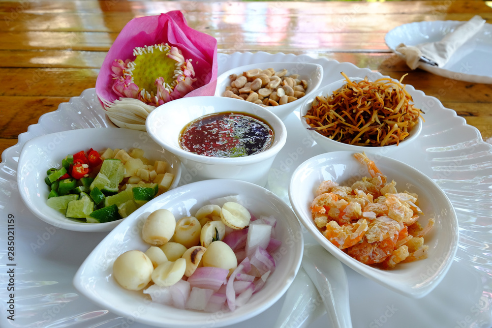 Royal leaf wrap appetizer, AKA Miang Kham in Thai, local traditional style food, prepared and served separately in white plate on wood table Royal leaf wrap appetizer, AKA Miang Kham in Thai, local traditional style food, prepared and served separately in white plate on wood table