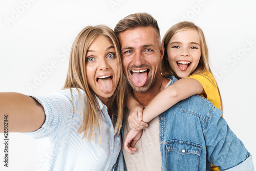 Image of funny caucasian family woman and man with little girl smiling and taking selfie photo together