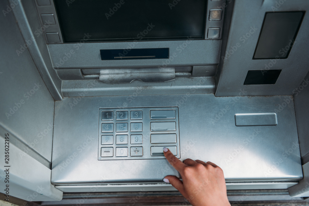 top view of woman pushing button on atm machine top view of woman pushing button on atm machine