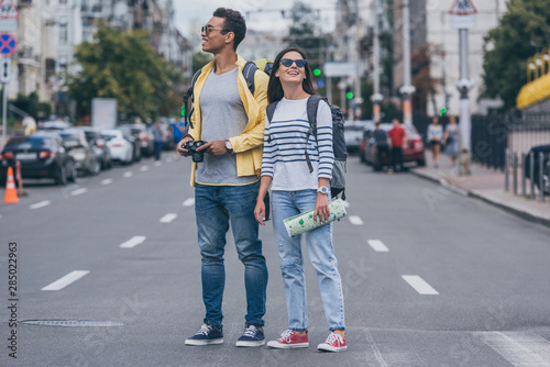 Woman holding map and standing on road near bi-racial friend with backpack and digital camera © LIGHTFIELD STUDIOS