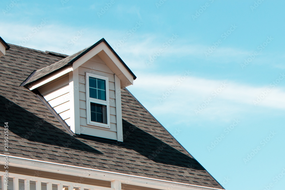 The close up image of authentic European house roof and roof window in blue sky with cloud.