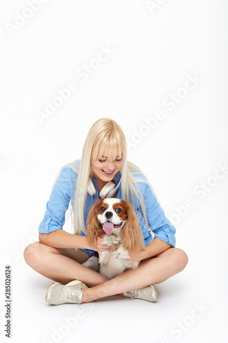 Blond pretty Woman trains a dog. Female Owner with her King Charles spaniel dog on white studio backgroundBlond pretty Woman hugs a dog. Female Owner with her spaniel dog on white studio background