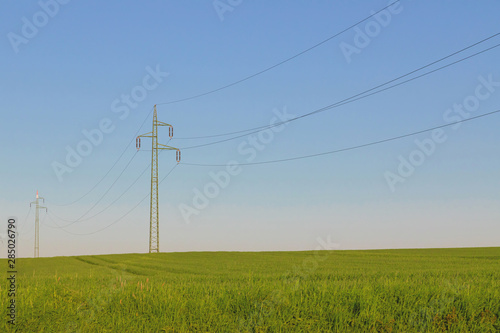 Power line and green field with blue sky