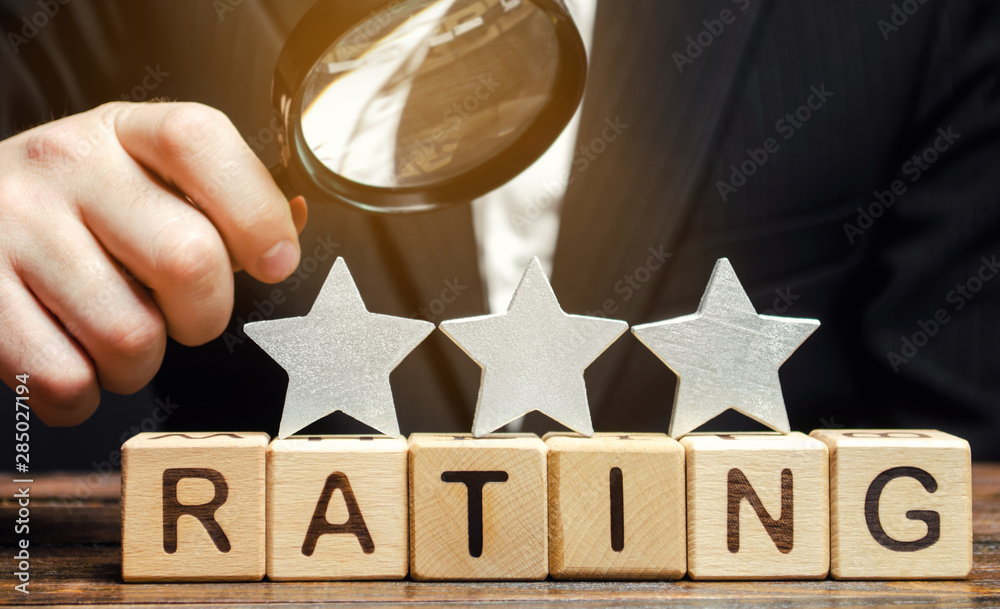 Φωτογραφία Wooden blocks with the word Rating, three stars and a magnifying glass in the hands of a businessman