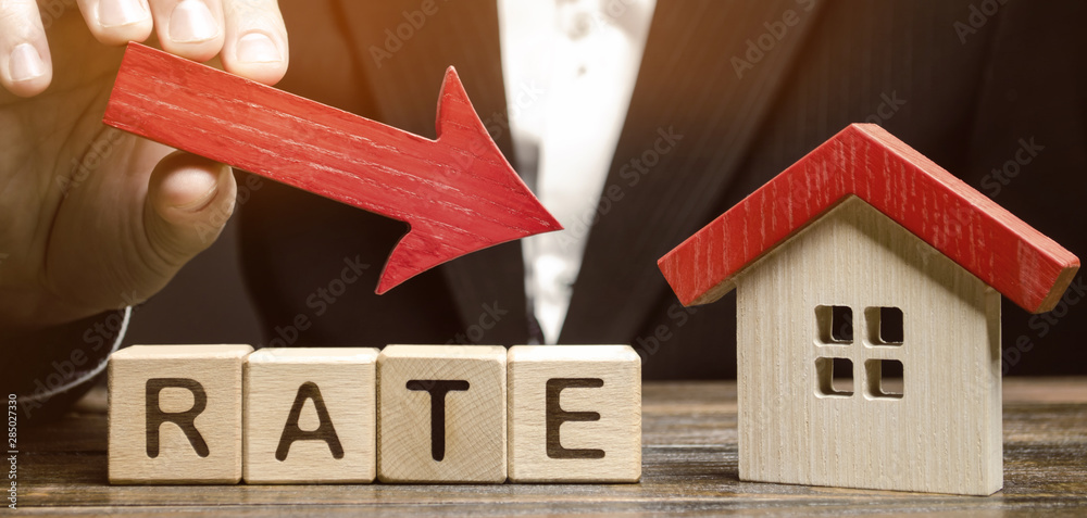 Φωτογραφία Businessman holding the down arrow on wooden blocks with the word Rate and house