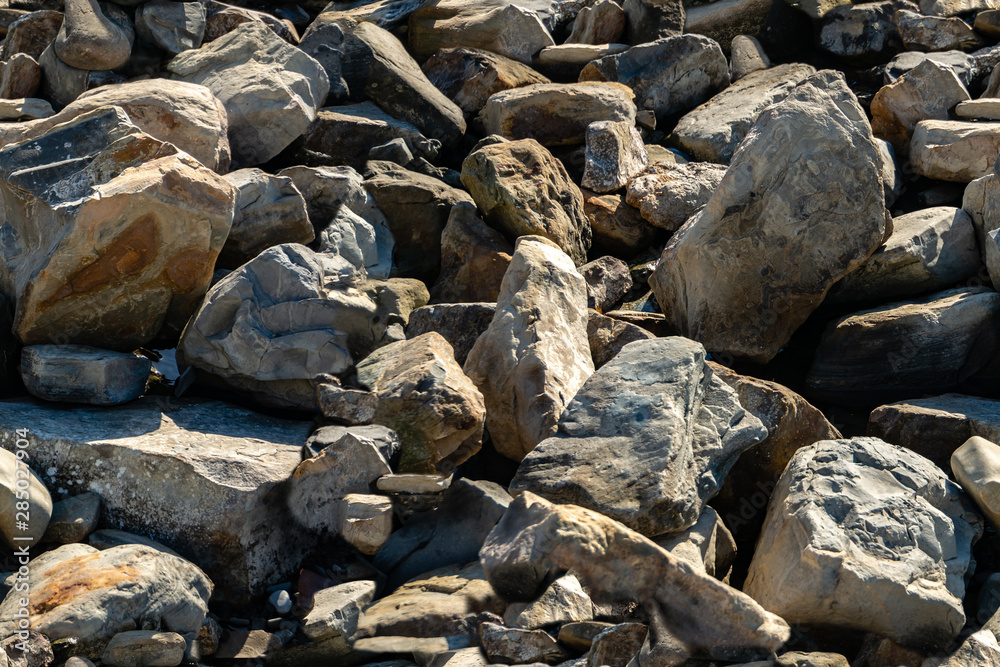 Seamless texture with sea stones and rocks of different sizes as original background. Natural stone of black, gray and brown on the Black Sea coast. Background from really nature