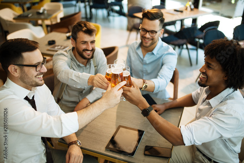 Handsome businessmen are drinking beer, talking and smiling while resting at the pub