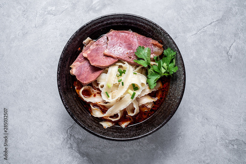 A bowl of nutritious and delicious beef noodles with noodles on a cement texture background