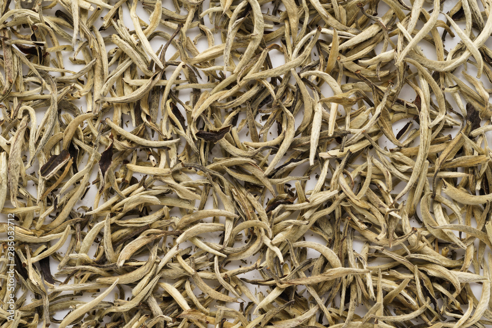 Dry white tea leaves as a background. Chinese Bai Hao Yin Zhen.