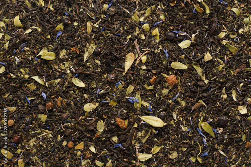 Dry black tea mixed with herbs and berries as a background. Dry black tea mixed with herbs and berries as a background.
