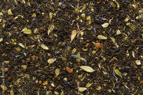 Dry black tea mixed with herbs and berries as a background.