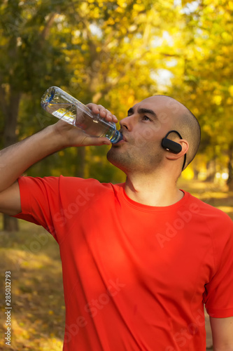 Young guy refreshing after exercise in park