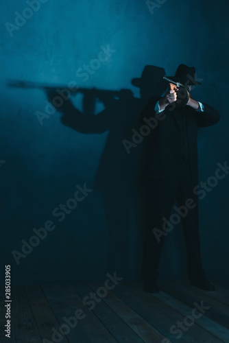 Retro gangster in hat shoots with machine gun.