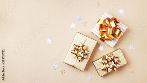 Gift or present boxes and stars confetti on golden table top view. Flat lay composition for birthday, christmas or wedding.