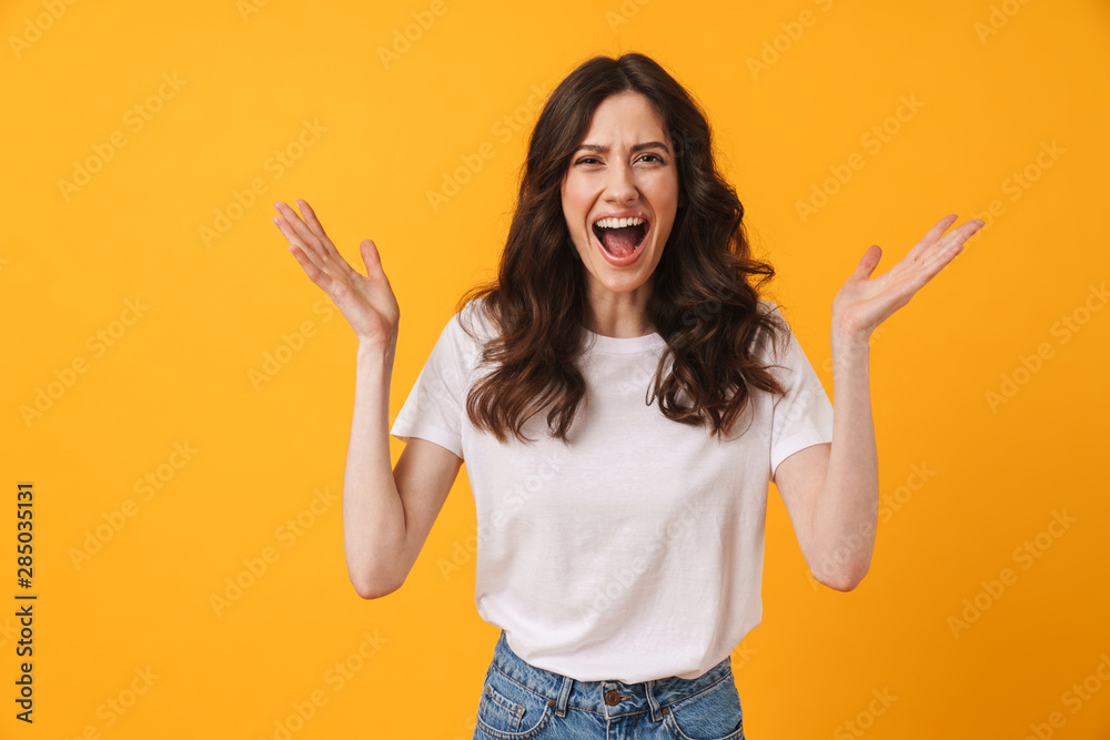 Emotional screaming young woman posing isolated over yellow wall background. Emotional screaming young woman posing isolated over yellow wall background.
