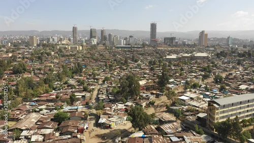 Flying over poor residential neighborhoods with rooftops made of corrugated sheet, contrast with looming modern skyline of Addis Ababa, urban development in Ethiopia Africa photo