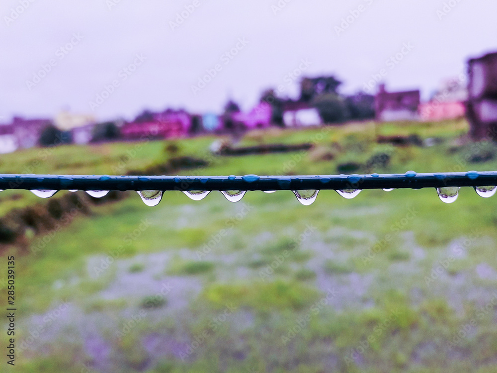 water droplets hangin under a wire in rainy season