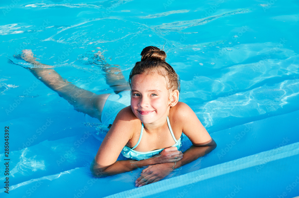 Cute smiling little girl child having fun in the swimming pool