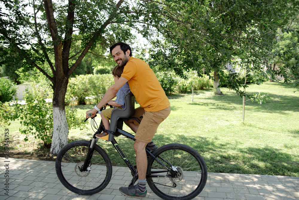 Bicycle ride of father and his son on baby seat