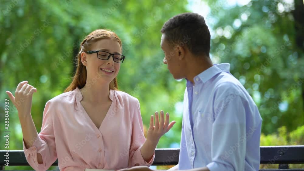 Teen girl in eyeglasses complaining her mixed-race boyfriend in park, bullying Teen girl in eyeglasses complaining her mixed-race boyfriend in park, bullying