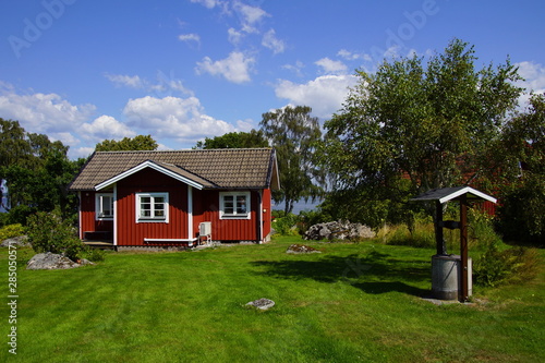 Traditional Swedish cottage in the countryside against a partly clouded blue sky Fototapeta