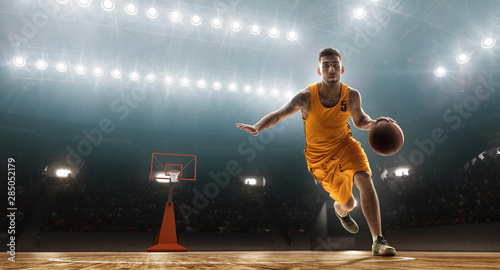 Professional basketball player dribbling. Floodlit sports arena photo