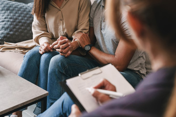 Cropped photo of casual nice couple having conversation with psychologist on therapy session in room