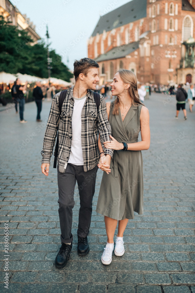 Happy loving couple smiling and walking throug the main square in Krakow (Cracow) Happy loving couple smiling and walking throug the main square in Krakow (Cracow)
